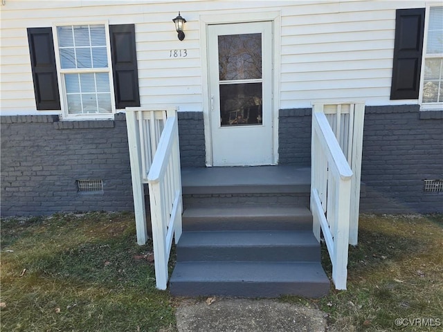 property entrance with crawl space and brick siding