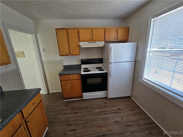 kitchen featuring dark wood-style floors, dark countertops, electric range, freestanding refrigerator, and under cabinet range hood