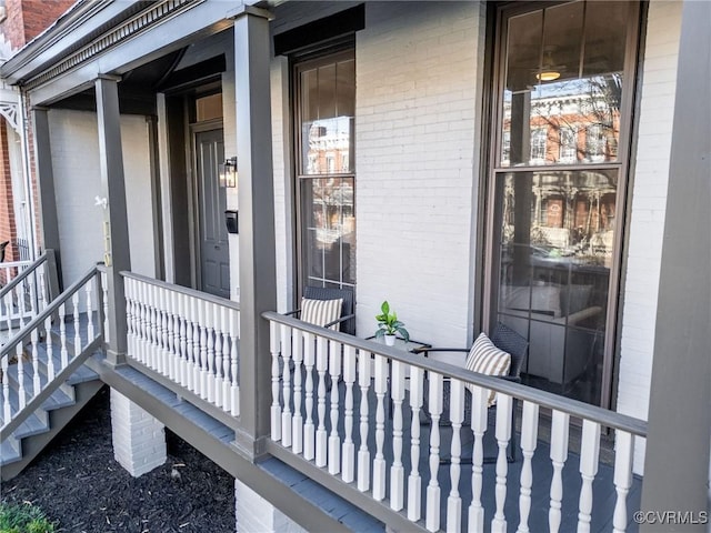 entrance to property featuring a porch and brick siding