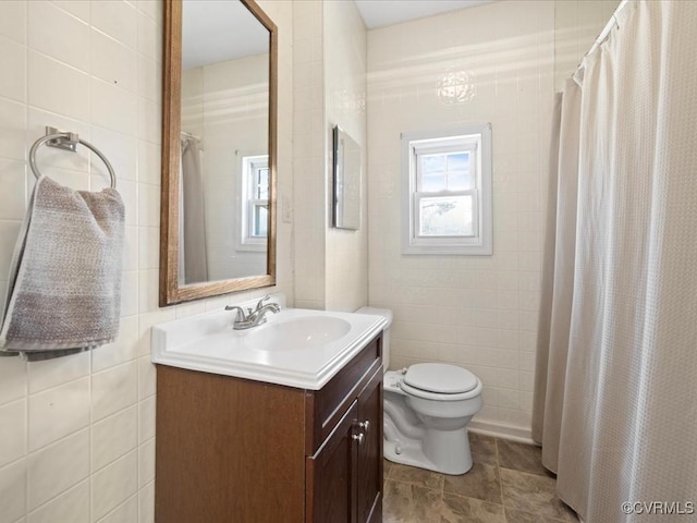 full bath with toilet, curtained shower, tile walls, and vanity