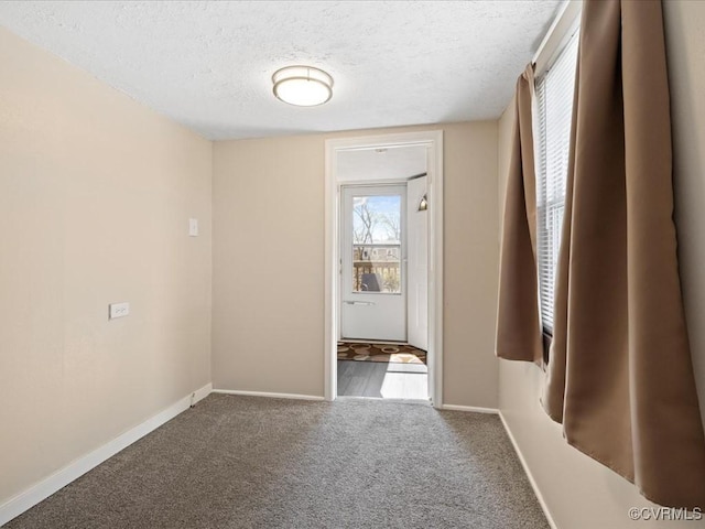 spare room with carpet, baseboards, and a textured ceiling