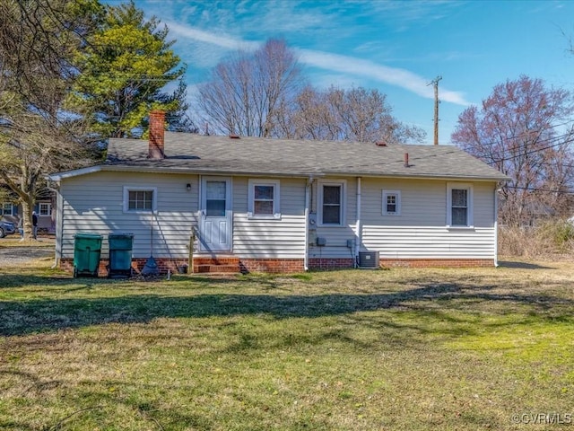 rear view of property featuring entry steps, central AC unit, a lawn, and a chimney