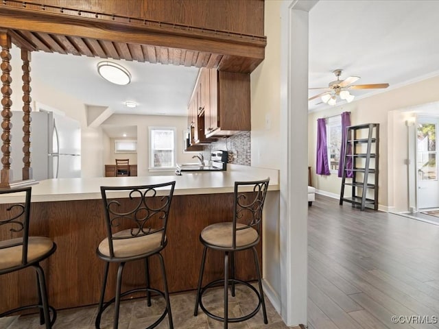 kitchen featuring a peninsula, wood finished floors, backsplash, and light countertops