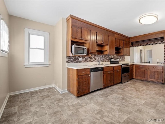 kitchen with a healthy amount of sunlight, appliances with stainless steel finishes, light countertops, and decorative backsplash