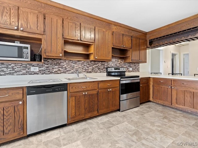 kitchen with brown cabinets, stainless steel appliances, light countertops, open shelves, and a sink