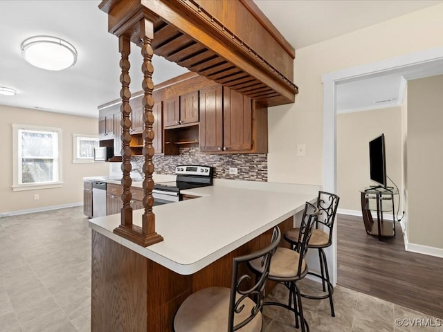 kitchen featuring a kitchen bar, appliances with stainless steel finishes, light countertops, and decorative backsplash