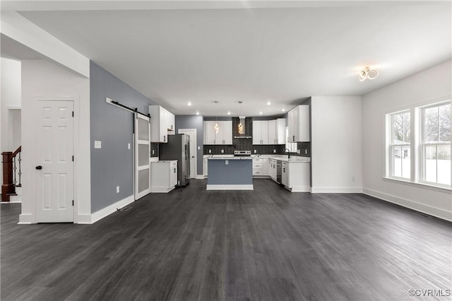 kitchen with a barn door, open floor plan, freestanding refrigerator, a center island, and wall chimney exhaust hood