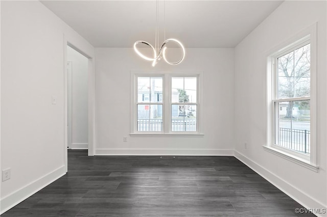 unfurnished dining area with dark wood-type flooring, baseboards, and an inviting chandelier