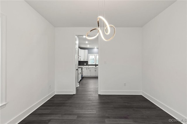 unfurnished dining area with an inviting chandelier, baseboards, and dark wood finished floors