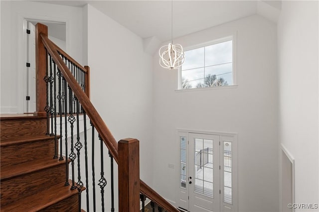 foyer featuring stairway, a towering ceiling, and an inviting chandelier