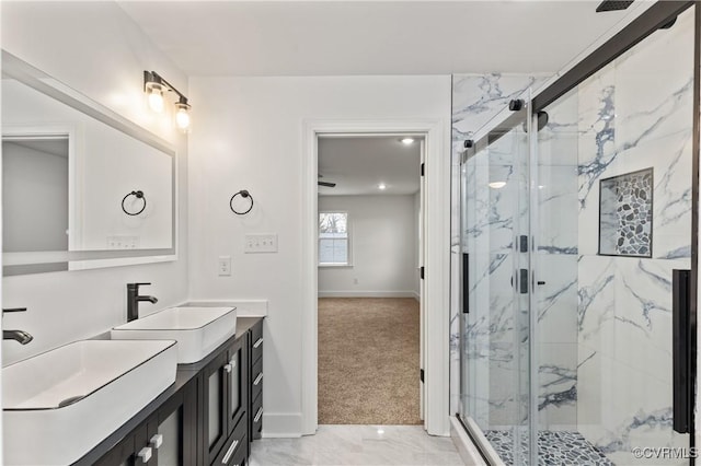 bathroom with marble finish floor, a marble finish shower, baseboards, and vanity