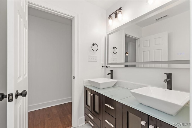 full bathroom featuring wood finished floors, a sink, visible vents, and baseboards