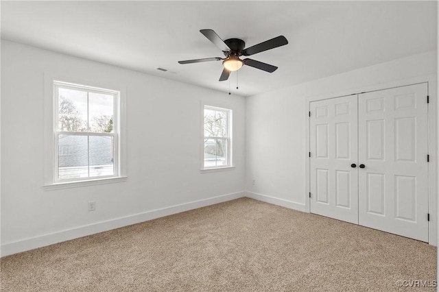 unfurnished bedroom with ceiling fan, carpet floors, visible vents, baseboards, and a closet