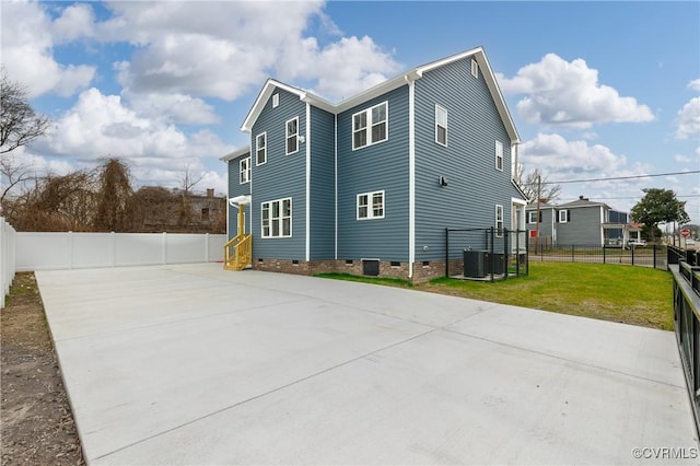 view of side of home featuring driveway, a lawn, crawl space, fence, and central air condition unit