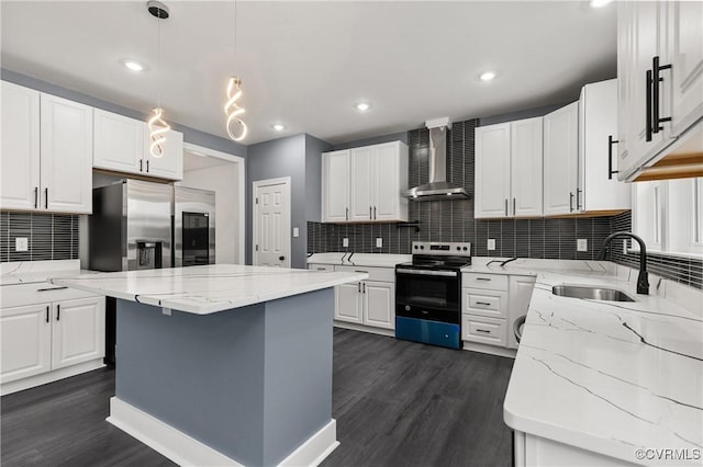 kitchen with dark wood finished floors, wall chimney exhaust hood, stainless steel appliances, white cabinetry, and a sink