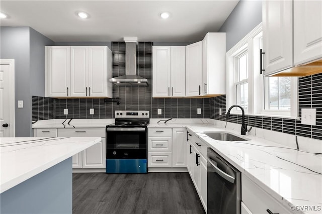 kitchen with wall chimney range hood, a sink, appliances with stainless steel finishes, and white cabinetry