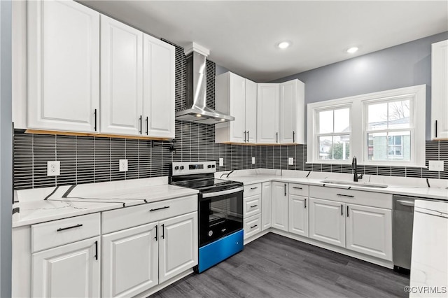 kitchen featuring dark wood-style floors, appliances with stainless steel finishes, white cabinets, a sink, and wall chimney exhaust hood