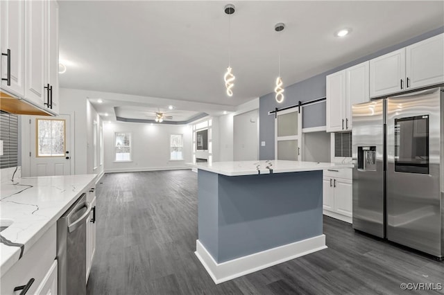 kitchen with stainless steel appliances, a ceiling fan, dark wood-type flooring, and a barn door