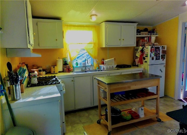 kitchen featuring a sink, range with gas stovetop, light countertops, and freestanding refrigerator