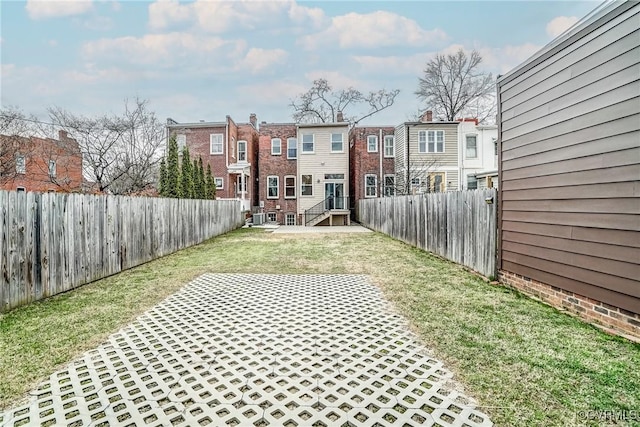 view of yard with entry steps, a fenced backyard, and a residential view