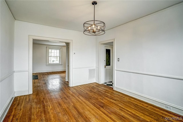 unfurnished dining area featuring visible vents, baseboards, a notable chandelier, and hardwood / wood-style floors