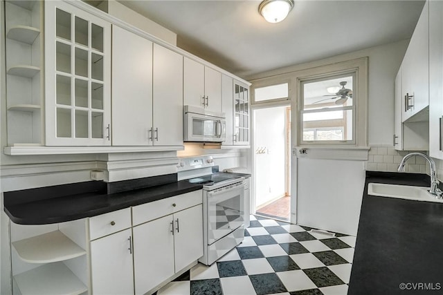 kitchen with white electric stove, open shelves, a sink, dark countertops, and dark floors