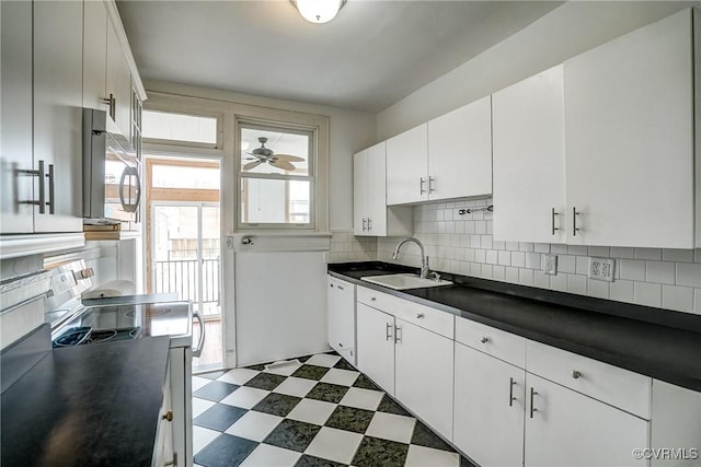 kitchen with dark countertops, dark floors, decorative backsplash, electric range, and a sink