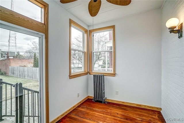 spare room with radiator, baseboards, a ceiling fan, and wood finished floors