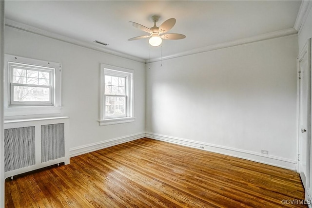 spare room featuring visible vents, radiator, crown molding, wood finished floors, and a ceiling fan