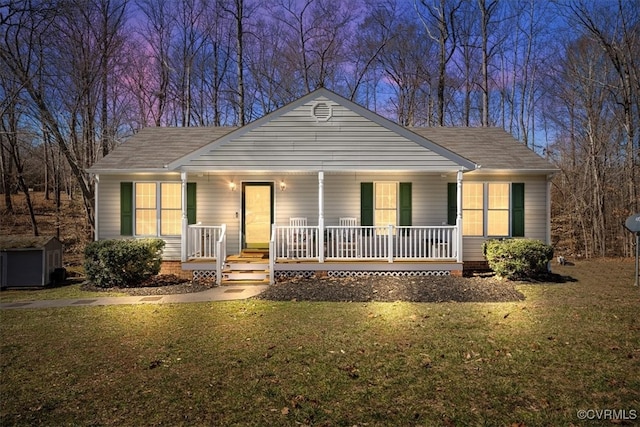 view of front of house featuring roof with shingles, a porch, a lawn, a shed, and an outdoor structure