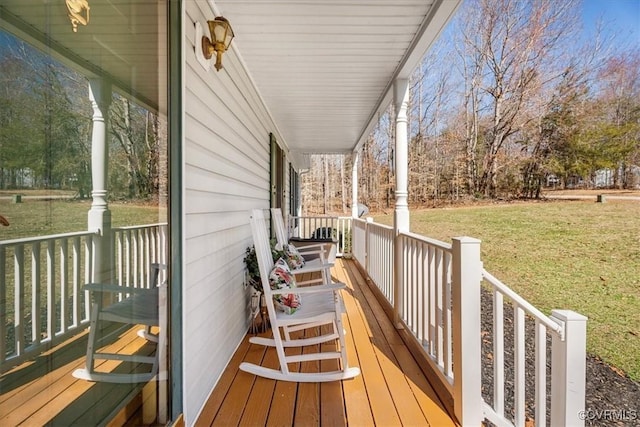 wooden terrace featuring covered porch and a lawn