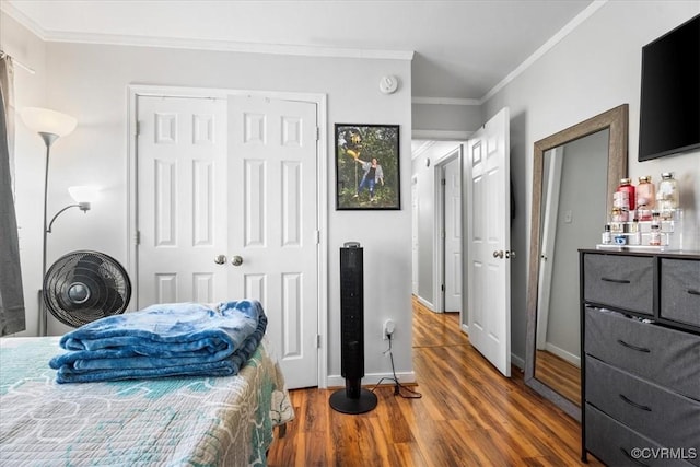 bedroom featuring baseboards, a closet, wood finished floors, and crown molding