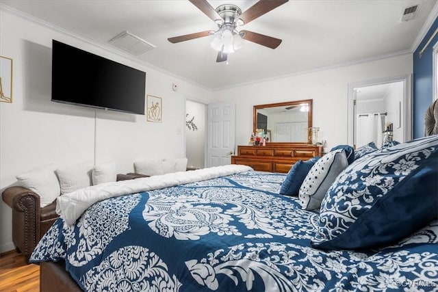 bedroom featuring ceiling fan, wood finished floors, visible vents, and crown molding