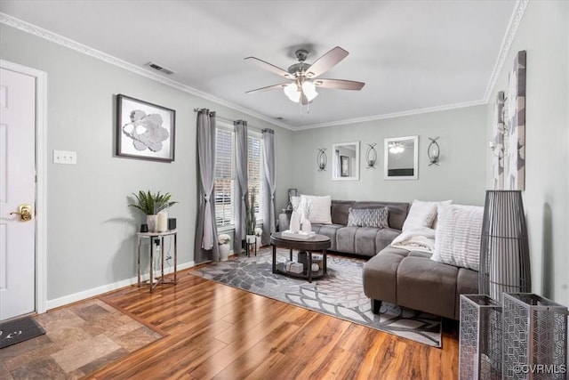 living room featuring baseboards, crown molding, visible vents, and wood finished floors