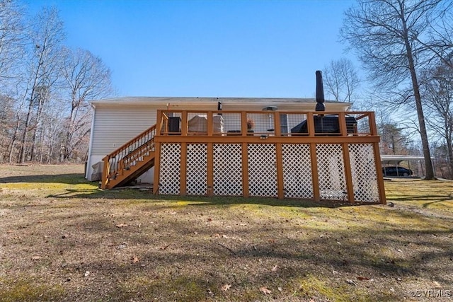 rear view of house featuring a deck, a lawn, and stairway