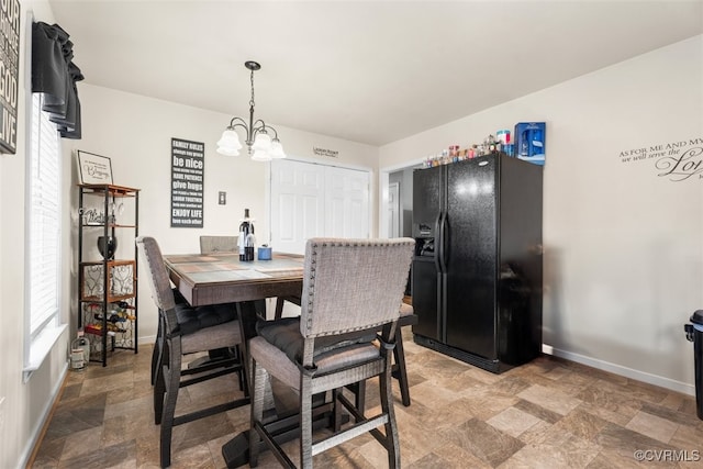 dining space featuring an inviting chandelier, stone finish flooring, and baseboards