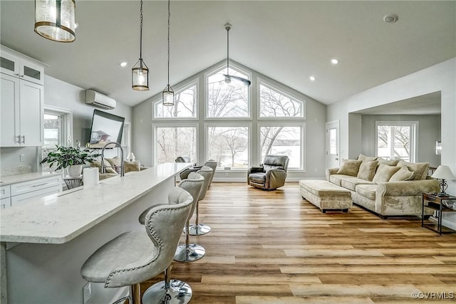 interior space with light wood-type flooring, white cabinets, a wall unit AC, and a breakfast bar area