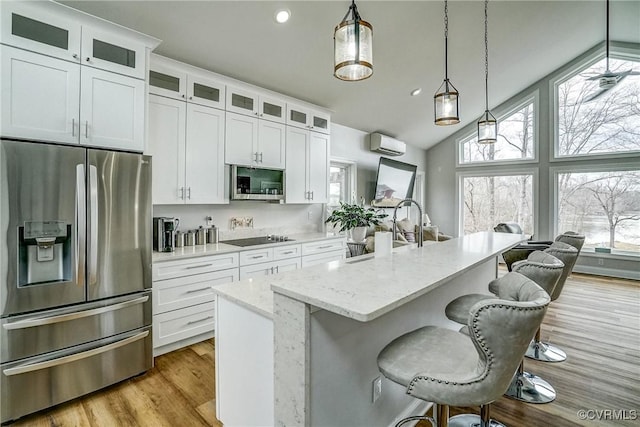 kitchen featuring appliances with stainless steel finishes, a kitchen island with sink, decorative light fixtures, and white cabinetry