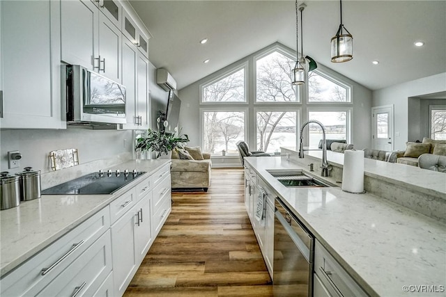 kitchen with glass insert cabinets, appliances with stainless steel finishes, open floor plan, wood finished floors, and a sink