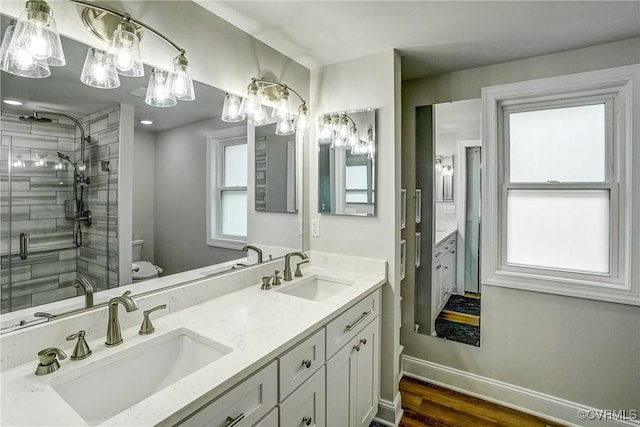 full bath featuring a stall shower, a sink, toilet, and baseboards