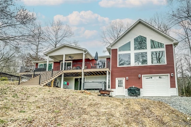 view of front of property with an attached garage, a ceiling fan, stairway, a wooden deck, and gravel driveway