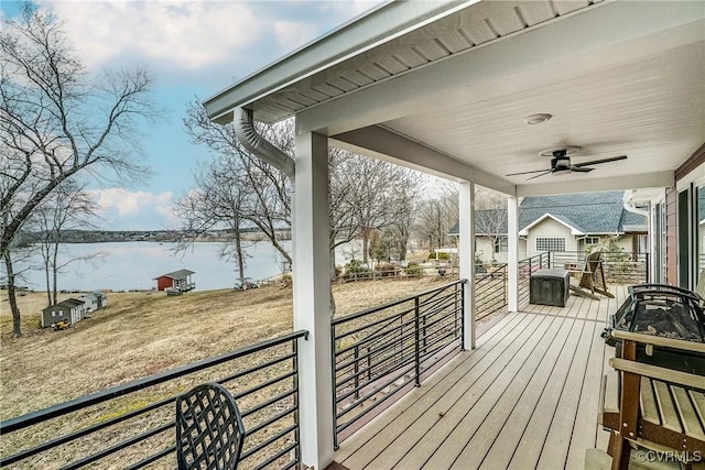 wooden terrace with a water view, ceiling fan, and a porch