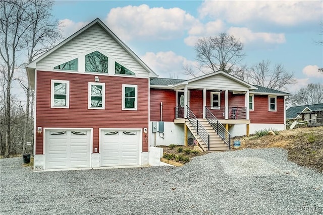 view of front facade featuring driveway, covered porch, a garage, and stairway