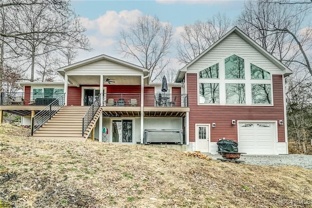 rear view of house with a garage, driveway, a ceiling fan, stairway, and a deck