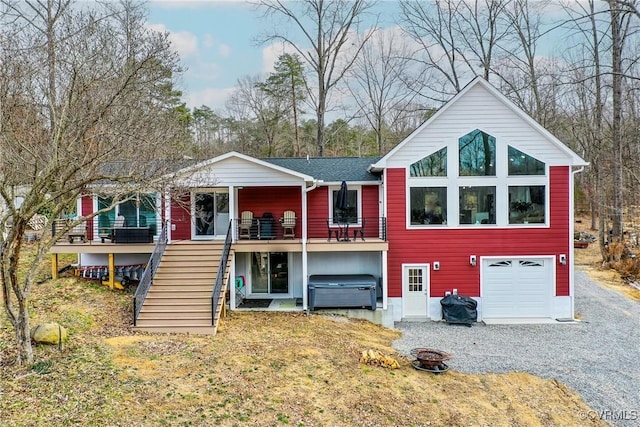 rear view of property with a garage, driveway, and stairway