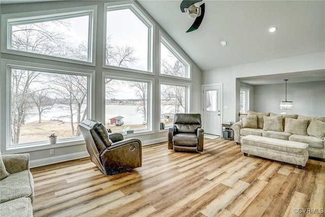 living area with high vaulted ceiling, wood finished floors, a wealth of natural light, and an inviting chandelier