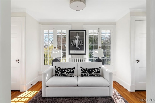 sitting room with baseboards, wood finished floors, and crown molding