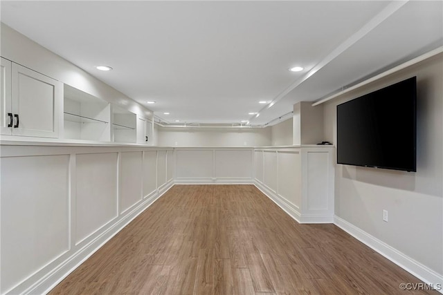 unfurnished room with recessed lighting, wood finished floors, and a decorative wall