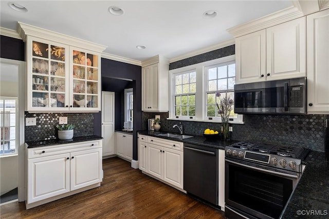 kitchen with ornamental molding, a sink, glass insert cabinets, dishwashing machine, and stainless steel range with gas stovetop