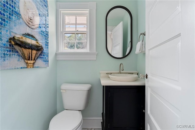 half bath featuring toilet, vanity, and baseboards